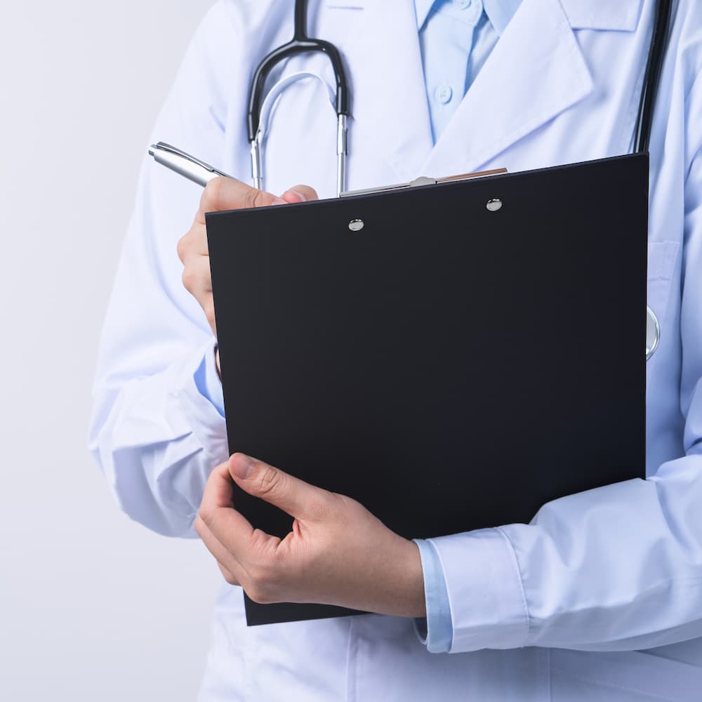 doctor-with-stethoscope-white-coat-holding-clipboard-writing-medical-record-diagnosis-isolated-white-background-close-up-cropped-view-1.jpg
